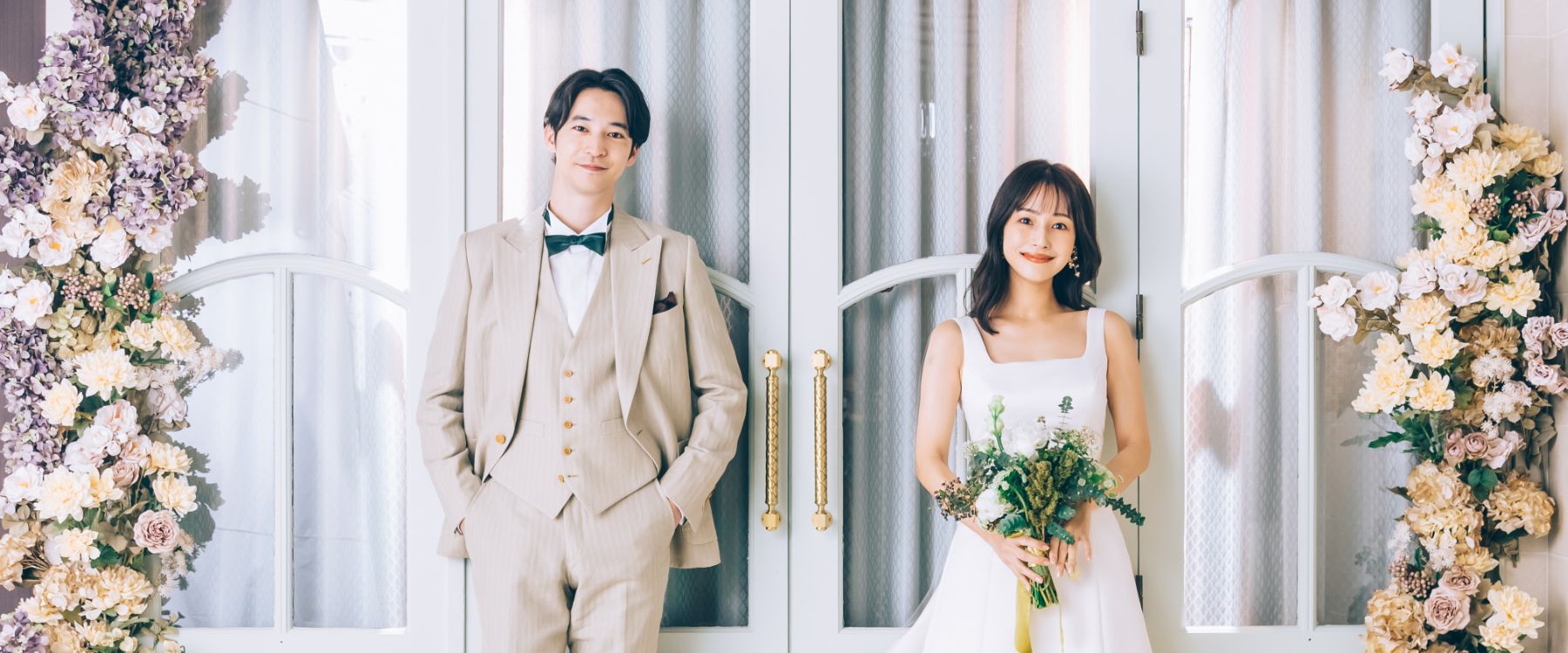 淡いグリーンの扉をバックに微笑む新郎新婦様の結婚写真