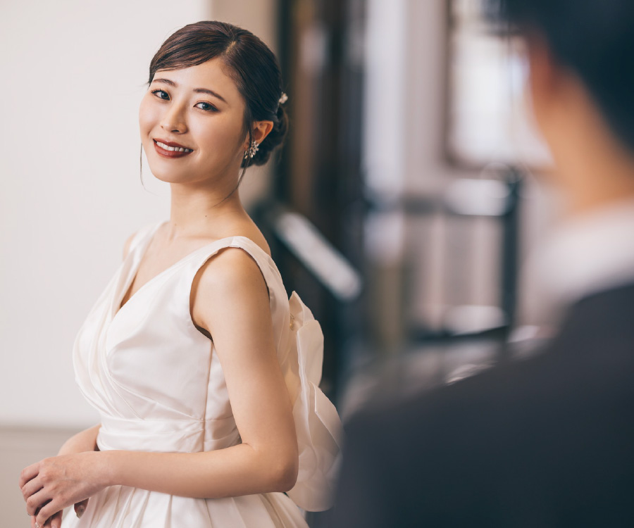 新郎様の方を笑顔で振り返る新婦様のウェディングフォト