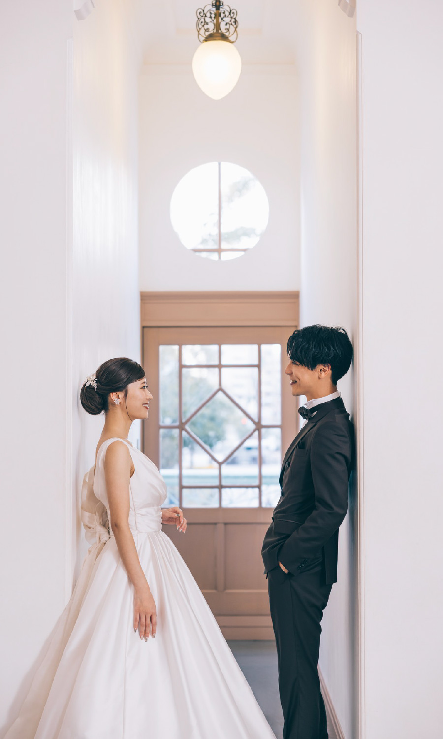 ランプが美しい廊下で見つめ合う新郎新婦様のウェディングフォト