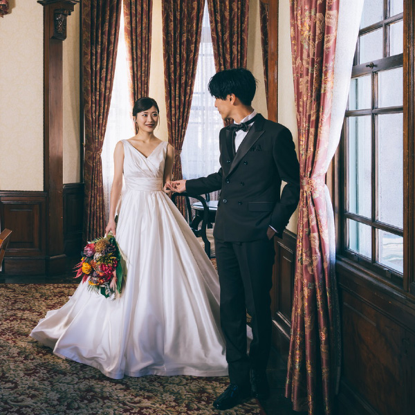 ブーケを持った新婦様をエスコートする新郎様の結婚写真