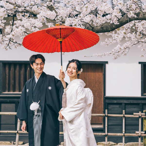 赤い和傘をさして並んで歩く新郎新婦様の結婚写真