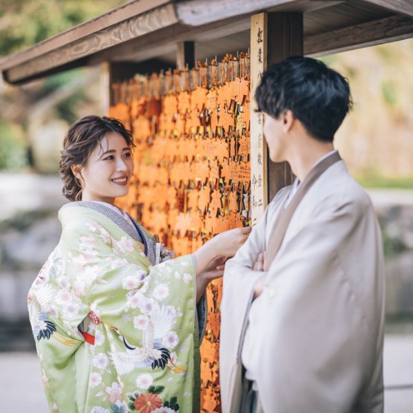 絵馬を見る新婦様を腕を組んで見守る新郎様の和装前撮り