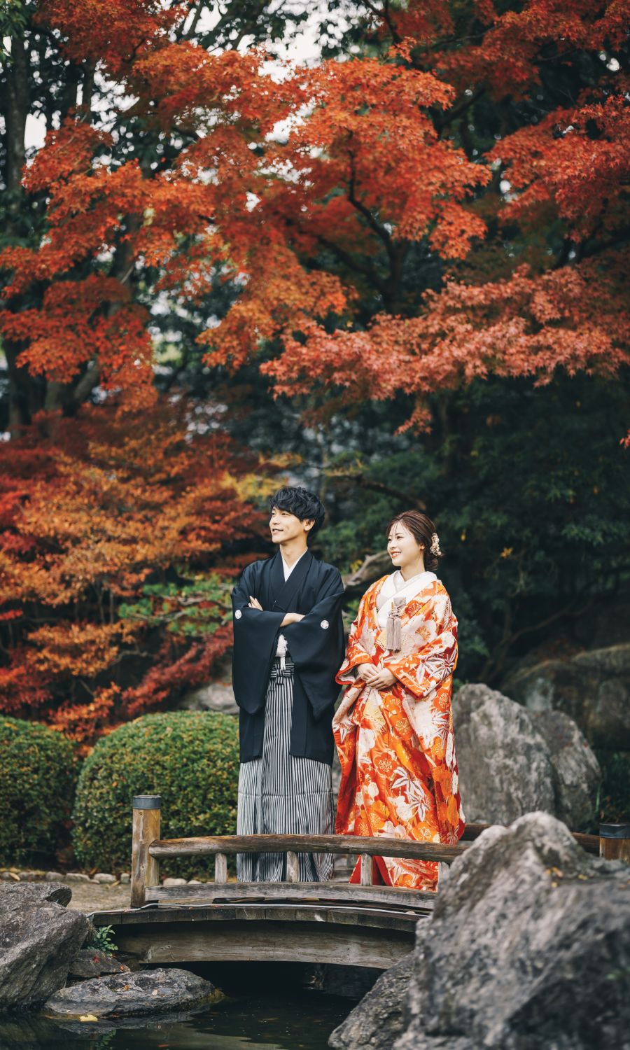 ダイナミックな紅葉をバックに橋の上で景色を眺める新郎新婦様