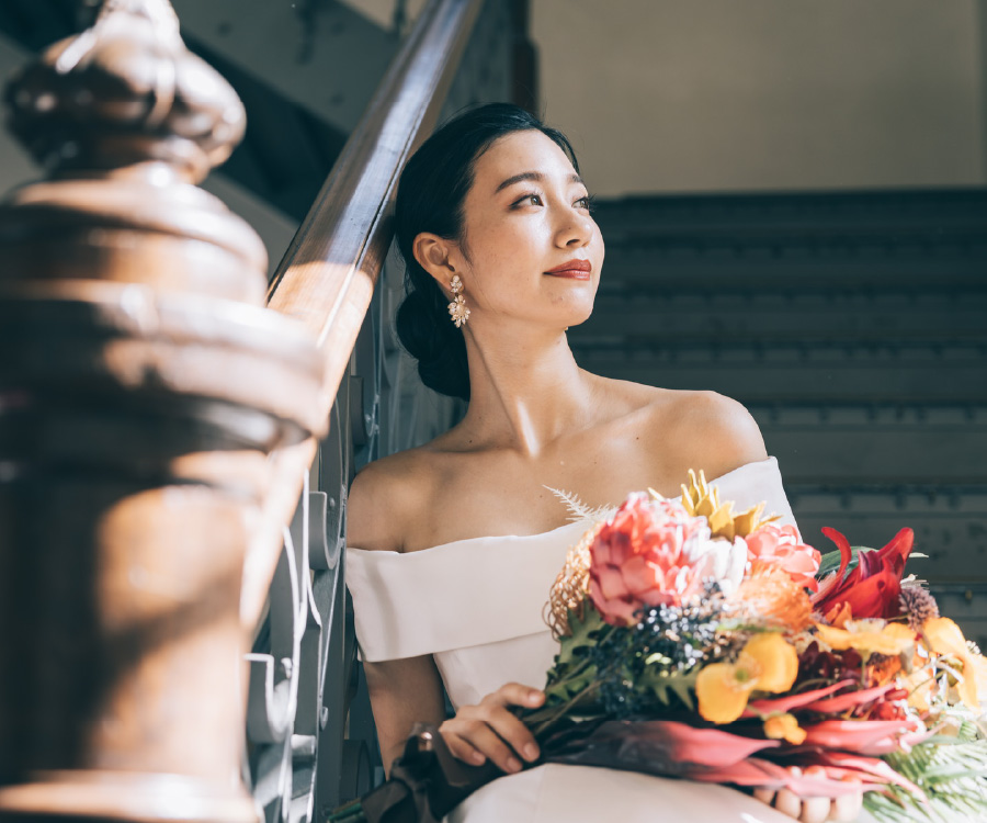 クラシカルな階段に座って窓の景色を眺める新婦様のソロショット