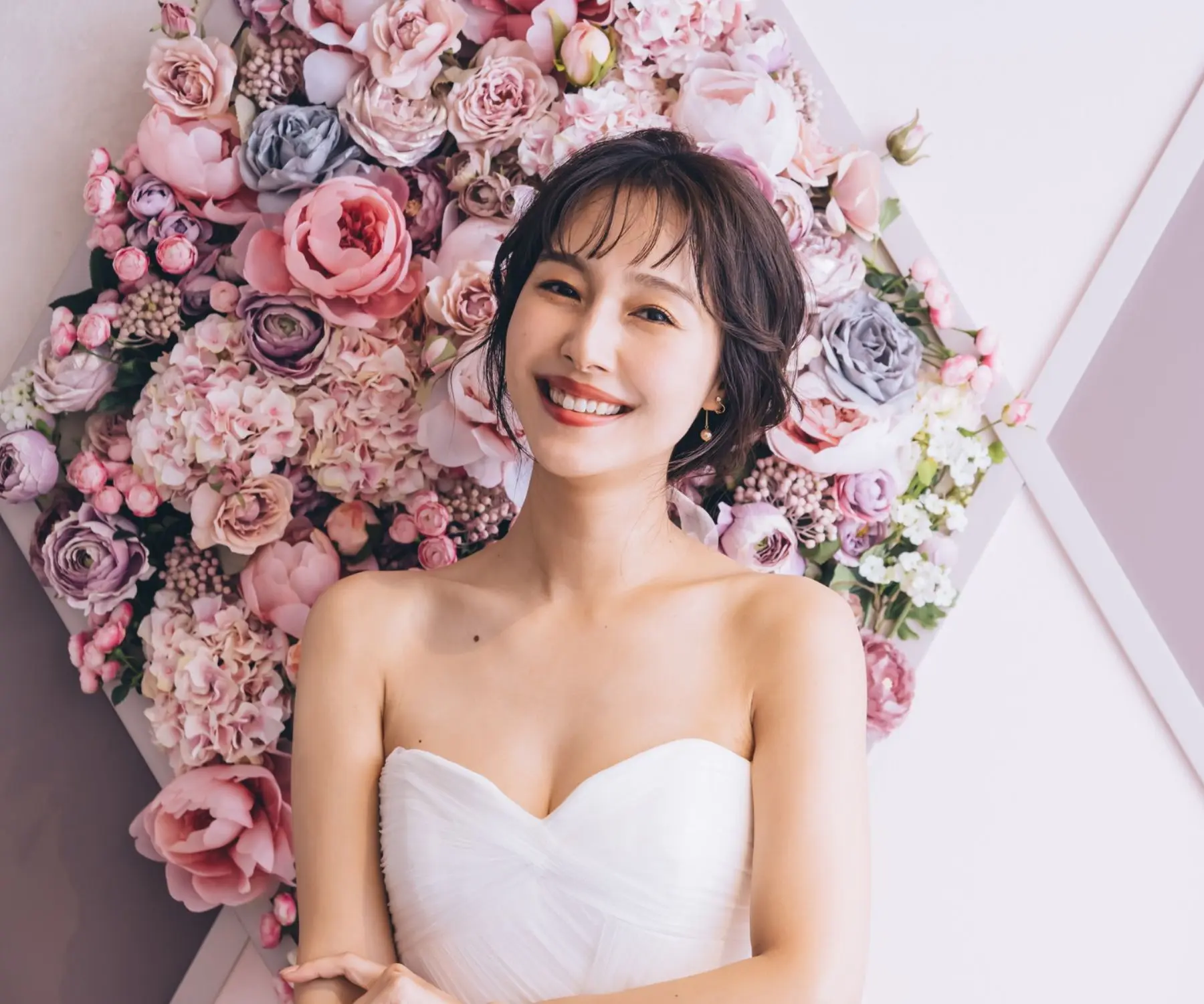                濃淡のあるピンク色のバラをバックに微笑む新婦様のアップショット     