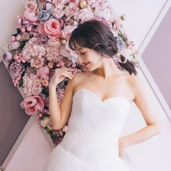                濃淡のあるピンク色のバラをバックにポーズをとる新婦様のソロショット     