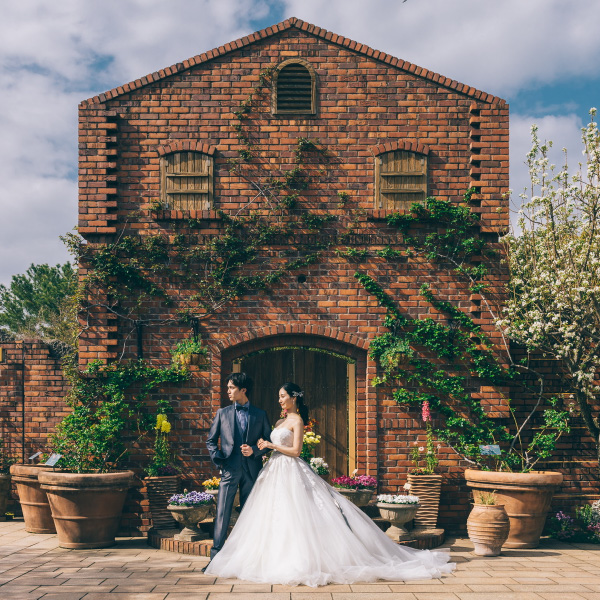 アンティークなレンガ造りの家の前で佇む結婚写真
