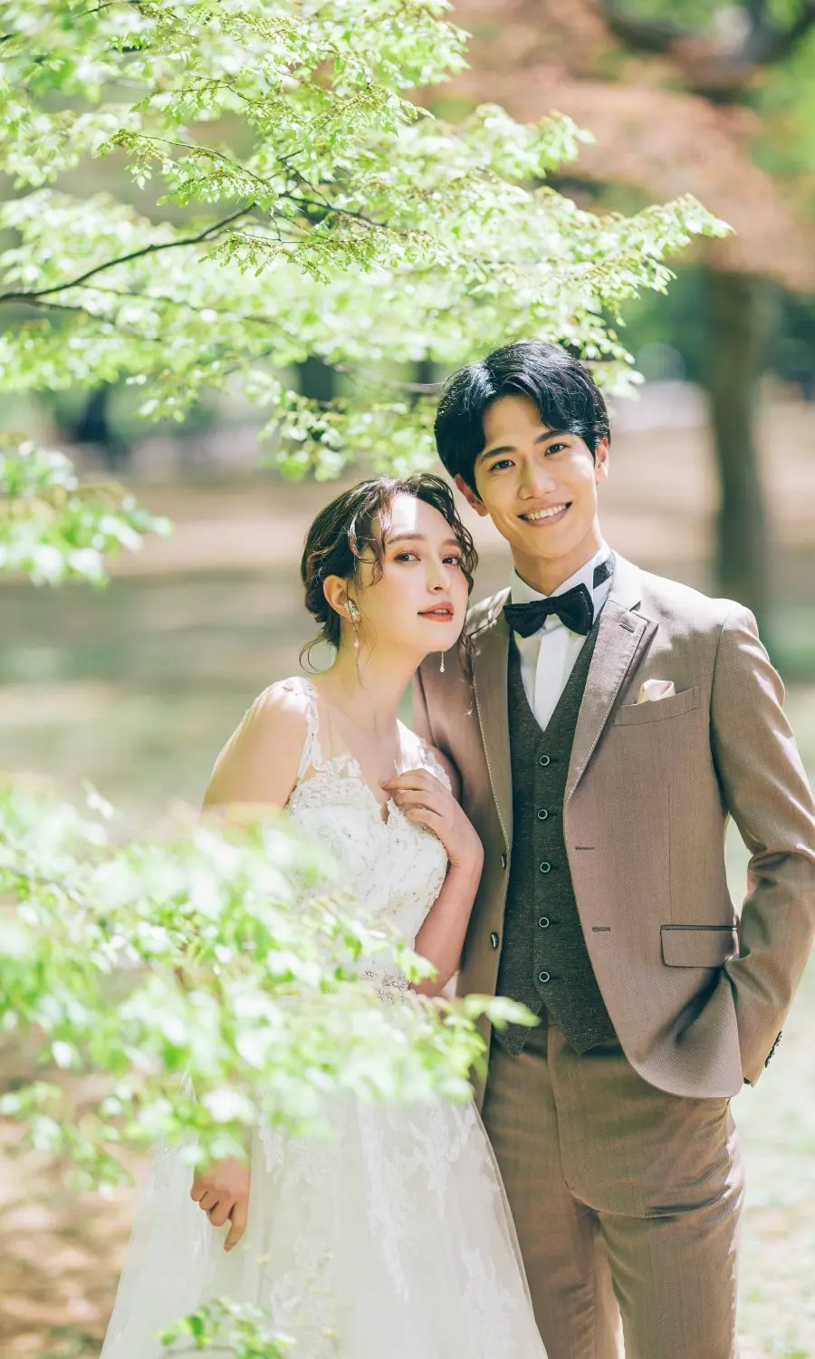 鮮やかな緑の中、背中をくっつけて笑う新郎新婦様のウェディングフォト