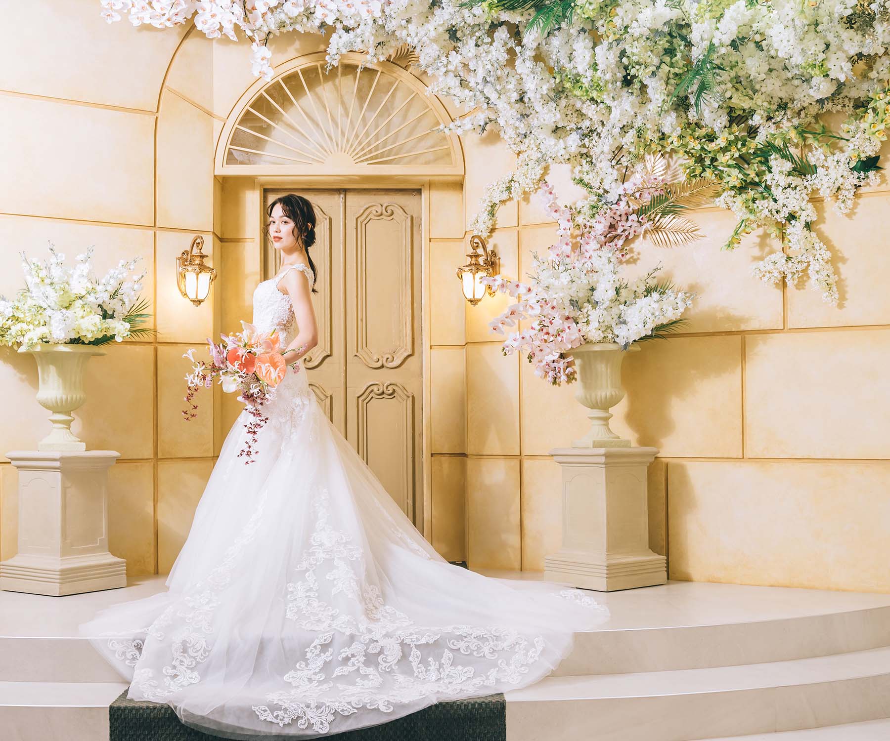                     ラグジュアリーな背景セットでポーズをとるブーケを持った新婦様の洋装全身ショット