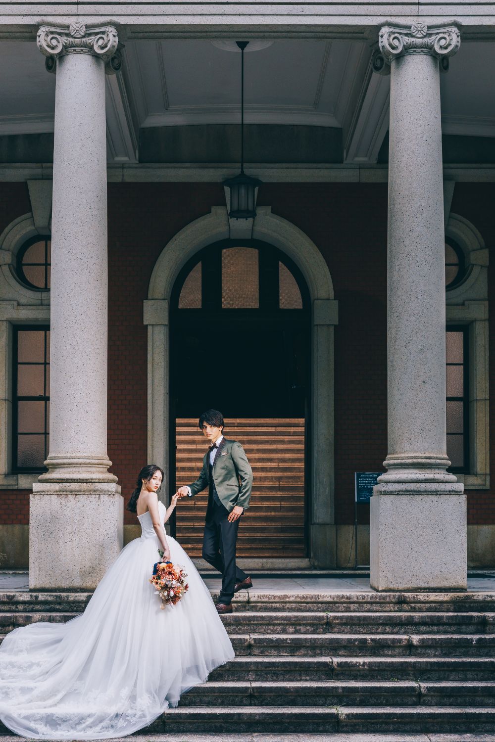 市政資料館前の階段で新婦様をエスコートする新郎様のウェディングフォト