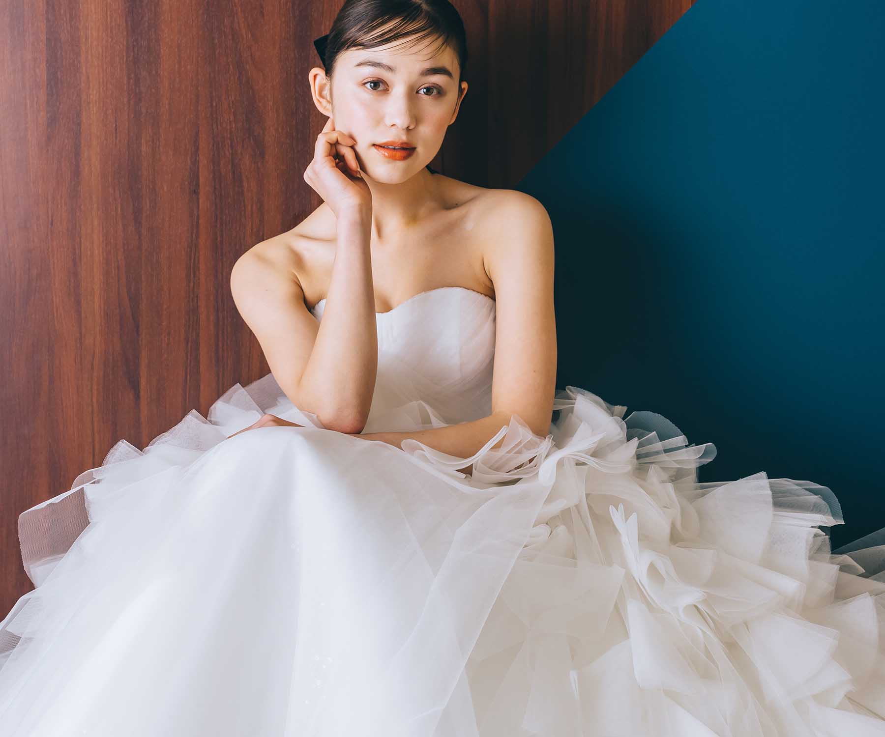                     座りながら膝に肘をつくウェディングドレスを着た新婦様のウェディングフォト