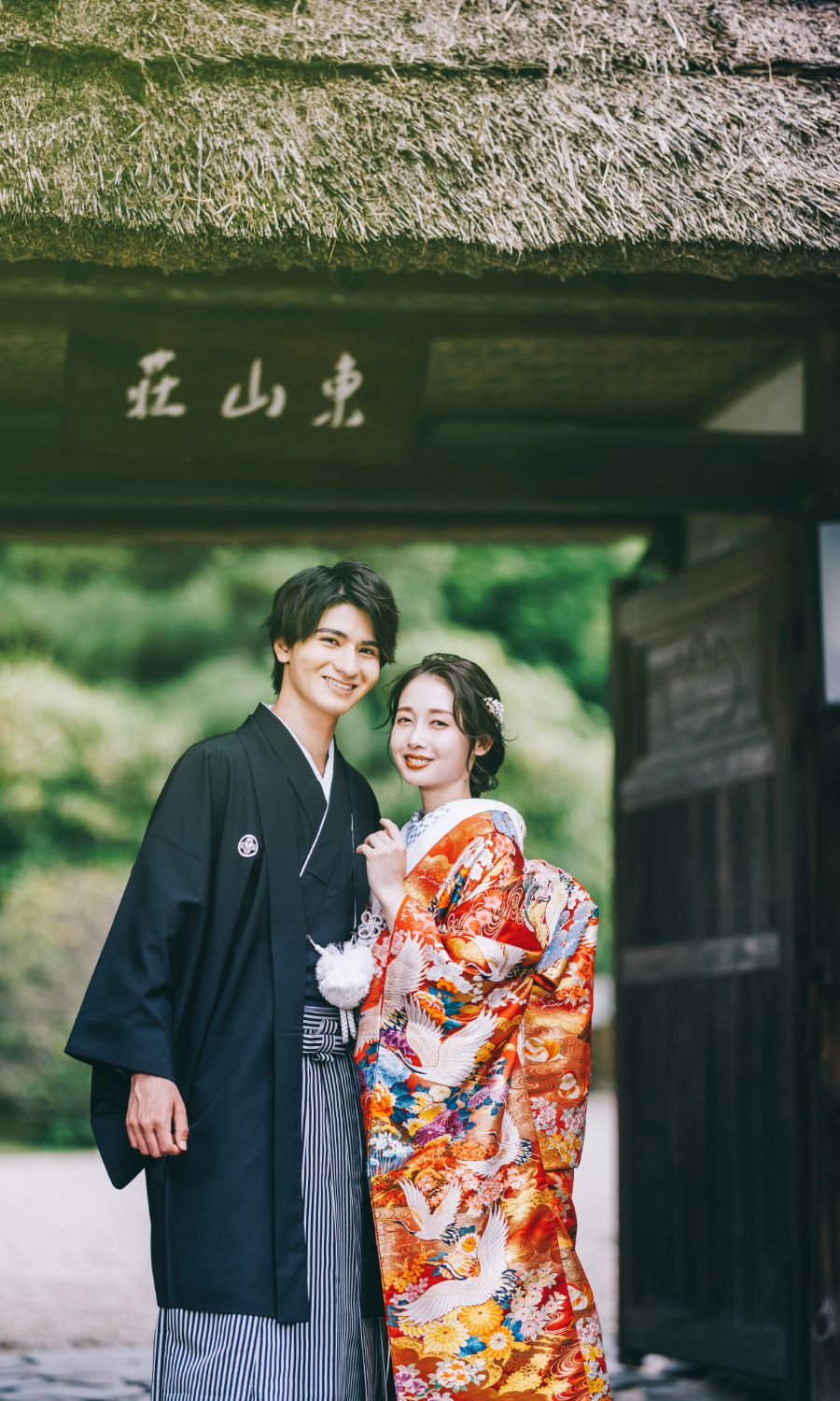 茅葺き屋根の下で寄り添う新郎新婦様の結婚写真