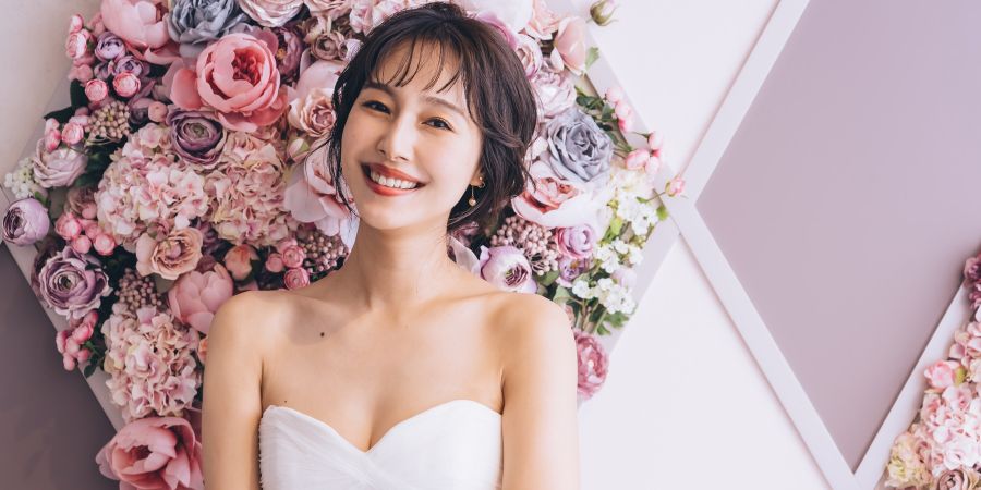 濃淡のあるピンク色のバラをバックに微笑む新婦様のソロショット