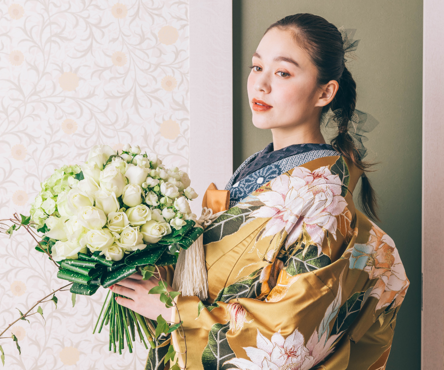                伝統的な和柄をバックに花束を見つめて微笑む新婦様の和装結婚写真     