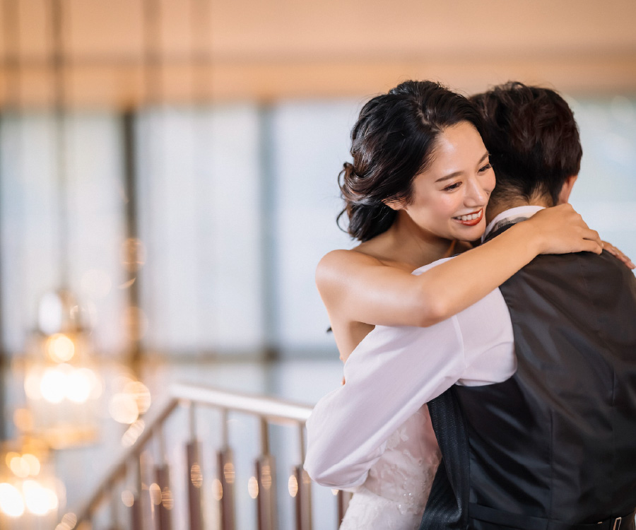 笑顔で新郎様とハグする新婦様のウェディングフォト