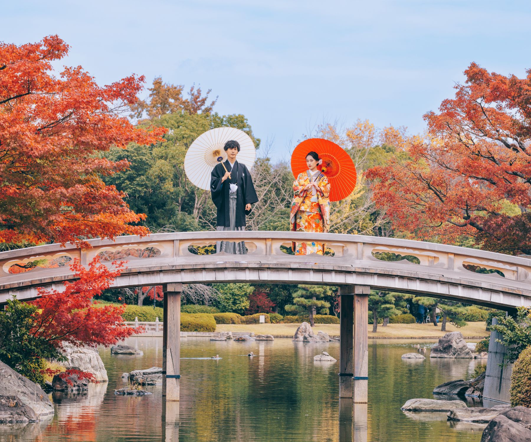 橋の上でそれぞれ赤と白の和傘をさす新郎新婦様の結婚写真