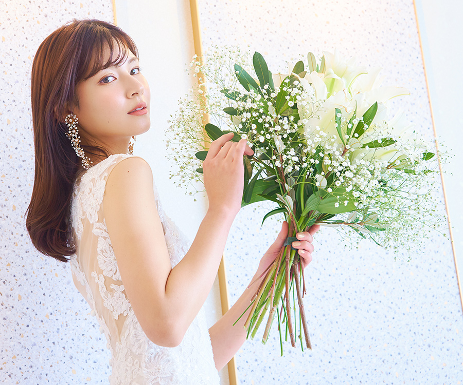           花束に触れるウェディングドレスを着た新婦様のソロショット          