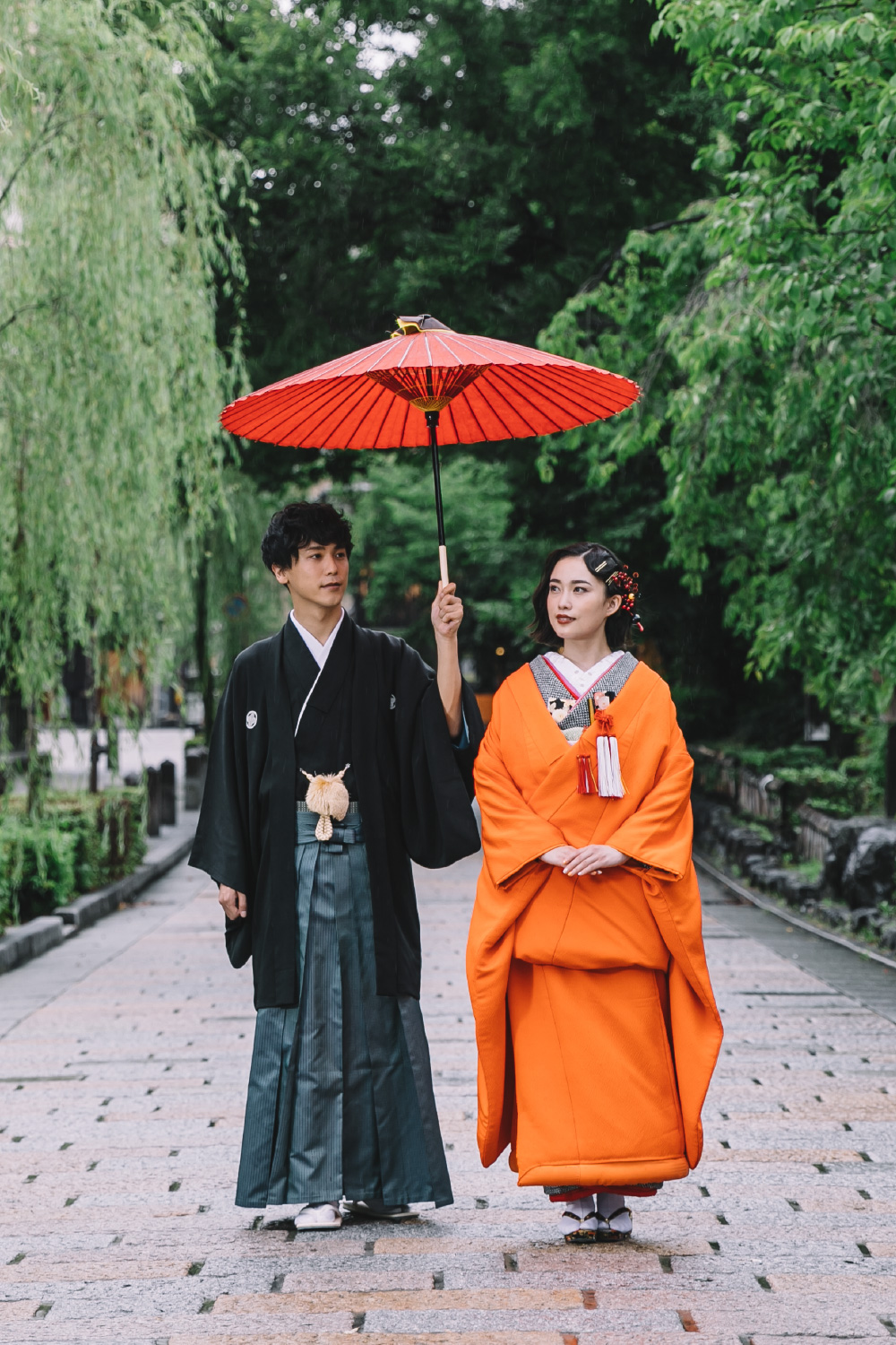 和傘を差しながら石畳の上を並んで歩く新郎新婦様の和装前撮り