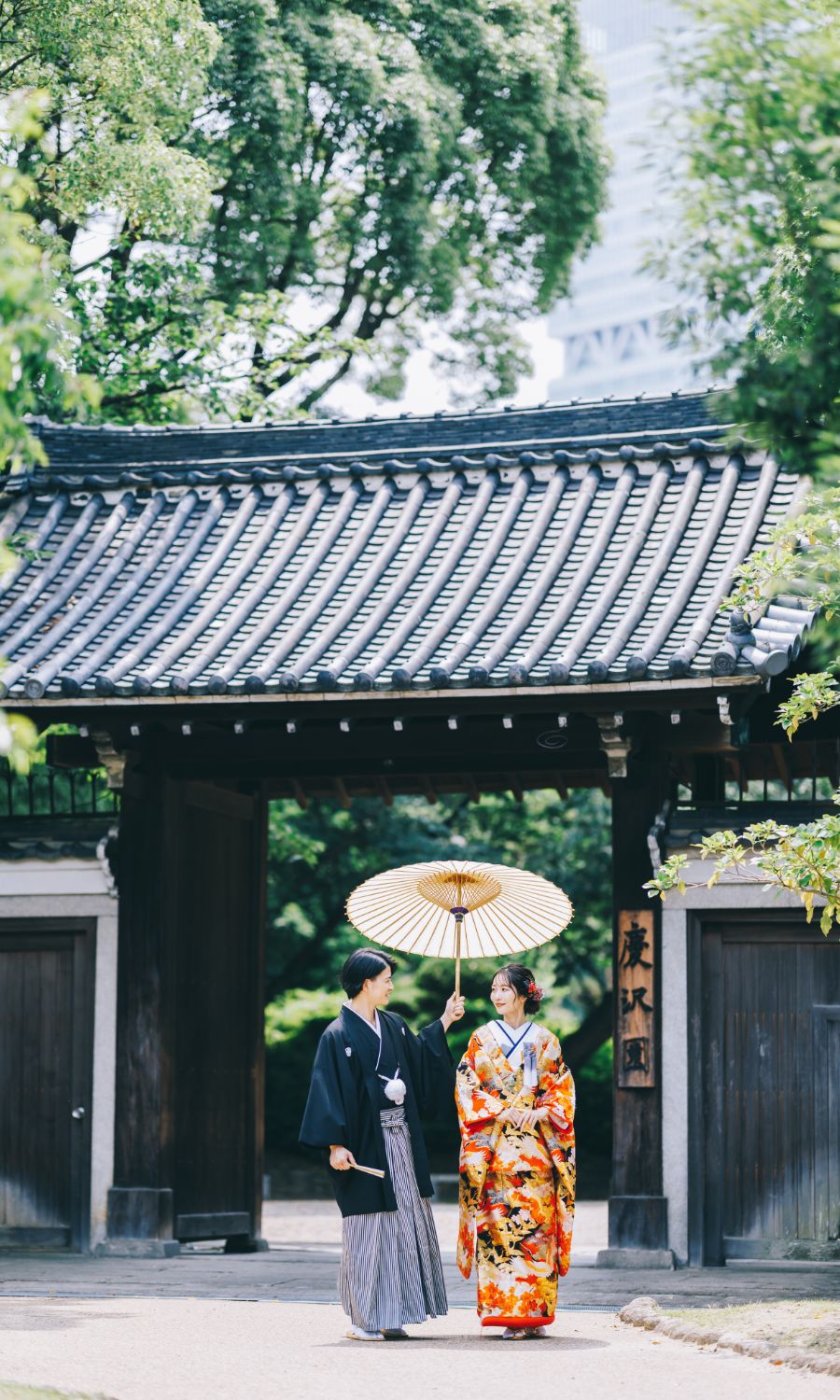 立派な門構えの前で見つめあう新郎新婦様