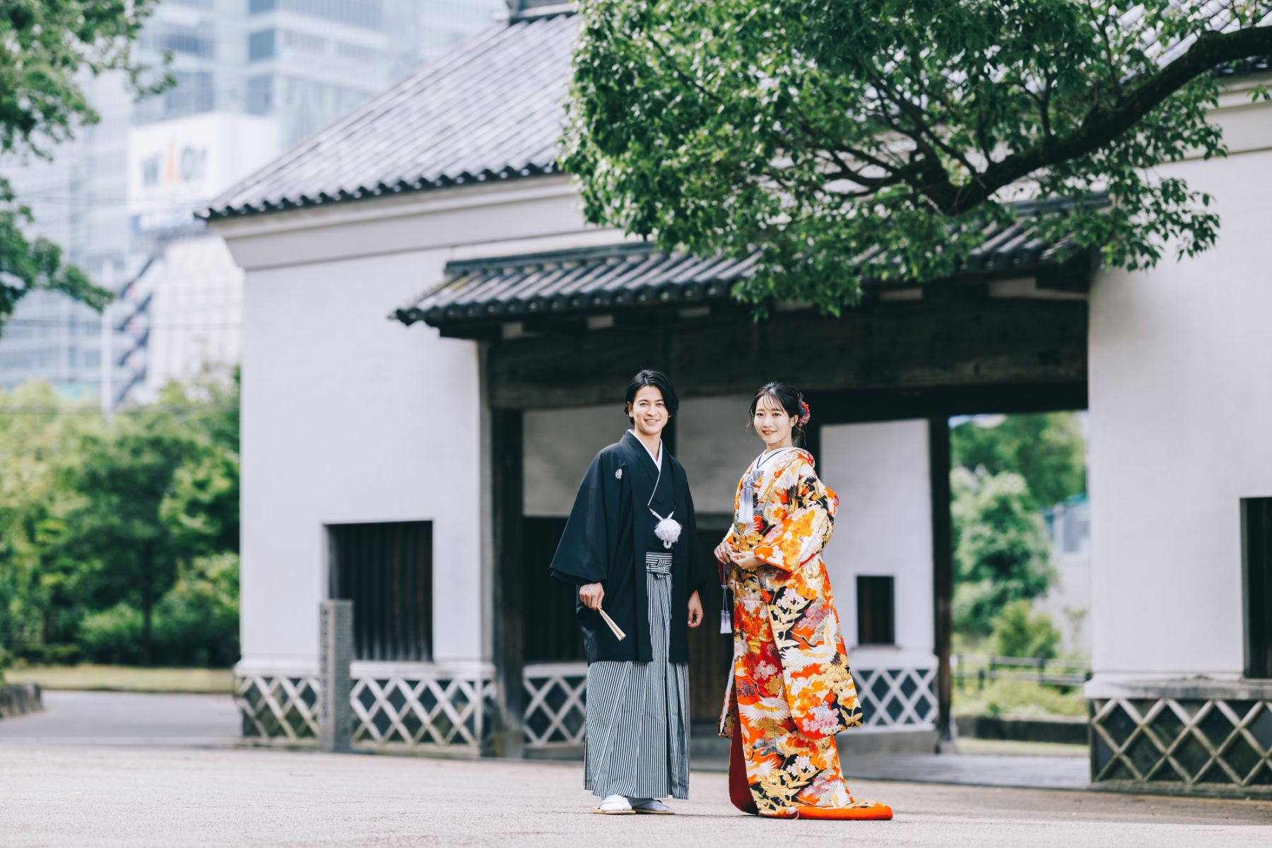 慶沢園の門をバックに微笑む新郎新婦様の和装全身ショット