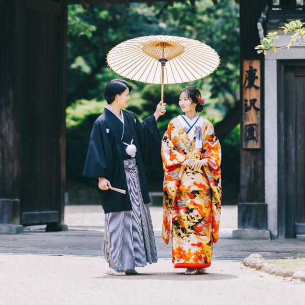 立派な門構えの前で見つめあう新郎新婦様