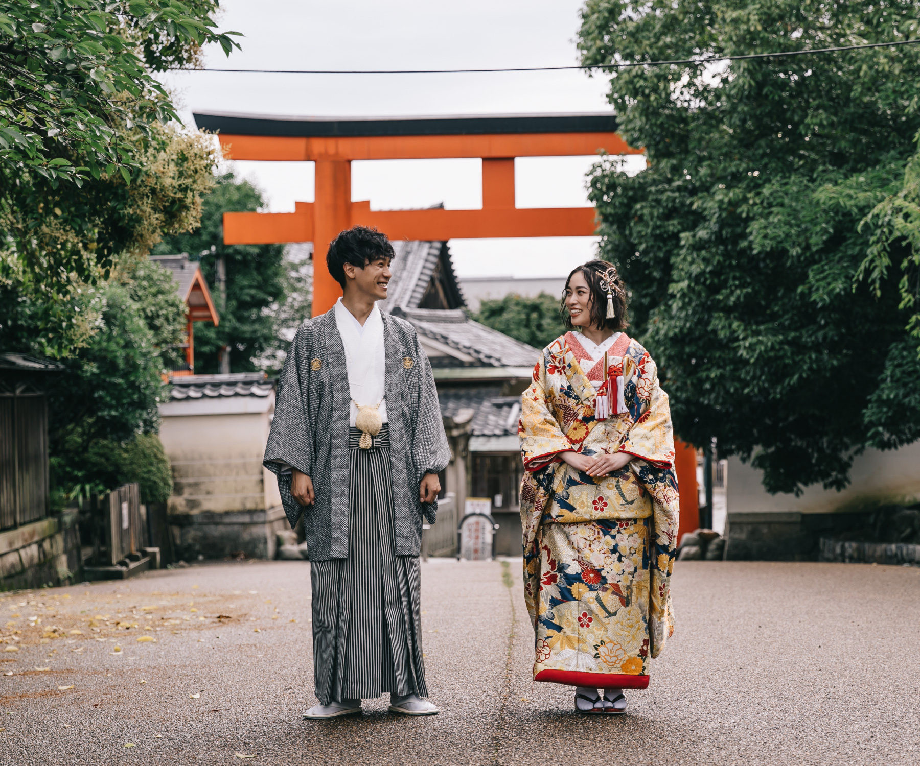 風情ある鳥居をバックに見つめ合いながら歩く新郎新婦様のロケーションフォト