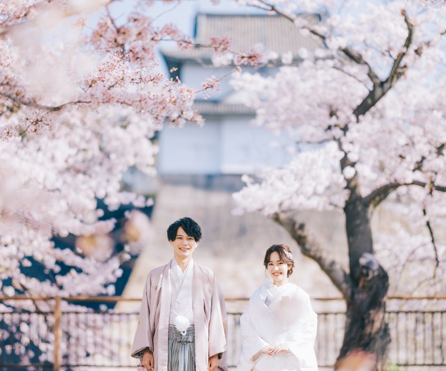 咲き誇る桜に囲まれて満面の笑みを浮かべる新郎新婦様の結婚写真