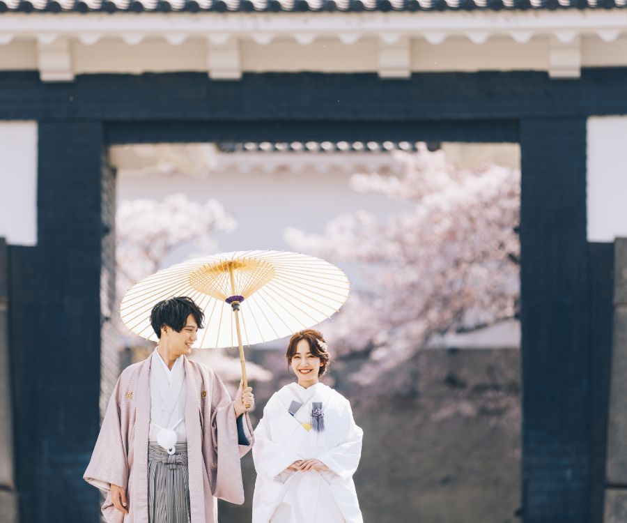 新婦様を優しく見つめながら相合傘をする新郎様のロケーションフォト
