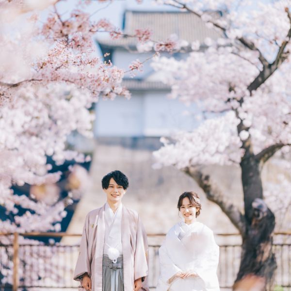 咲き誇る桜に囲まれて満面の笑みを浮かべる新郎新婦様の結婚写真