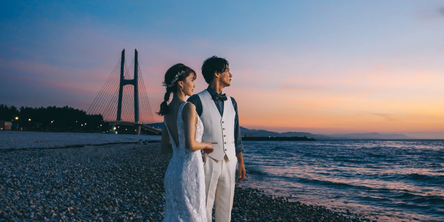 美しい夕焼けと空のグラデーションをバックに海を眺める新郎新婦様のロケーションフォト