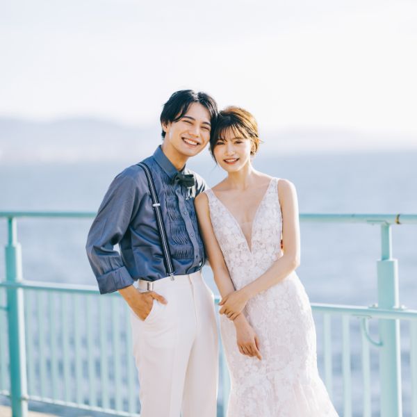 海をバックに寄り添う新郎新婦様のウェディングフォト
