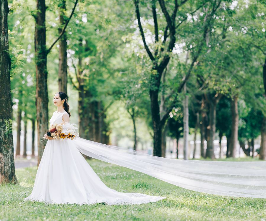 花束を抱えた新婦様のドレスがなびいているロングショット