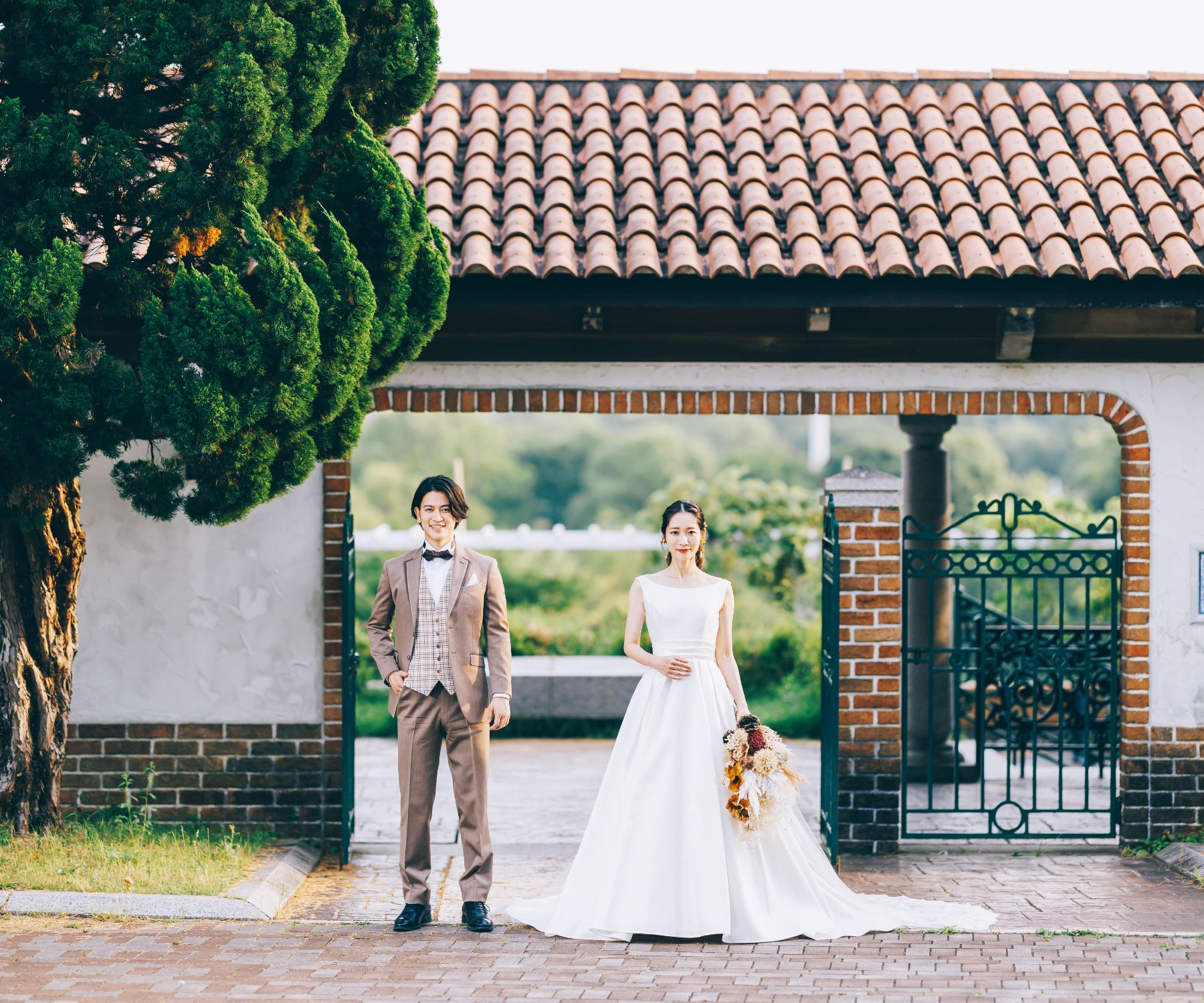 瓦とレンガがマッチしたレトロモダンな建物をバックにポーズをとる新郎新婦様の結婚写真