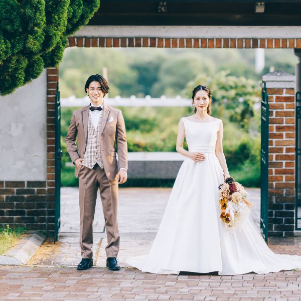 瓦とレンガがマッチしたレトロモダンな建物をバックにポーズをとる新郎新婦様の結婚写真