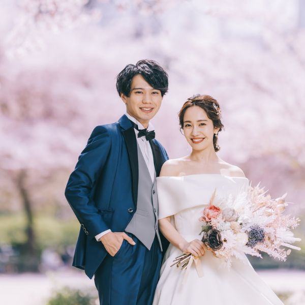 満面の桜をバックに体を寄せて微笑む新郎新婦様のウェディングフォト
