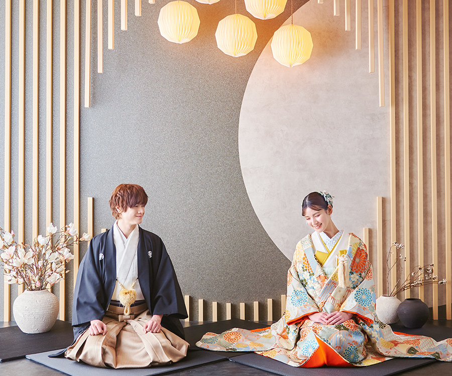           提灯のほのかな光が空間を包む背景セットをバックに正座をして微笑む新郎新婦様の和装前撮り          