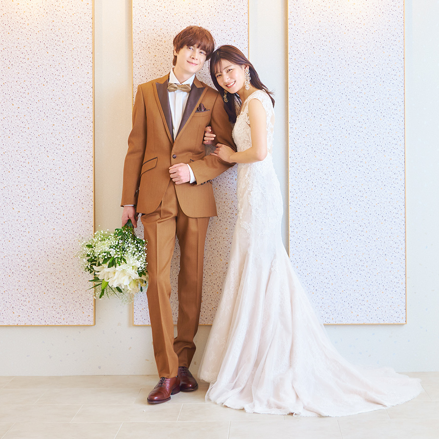           柔らかい白と淡いピンクを基調にしたニュートラルな背景セットをバックに寄り添う新郎新婦様のウェディングフォト          