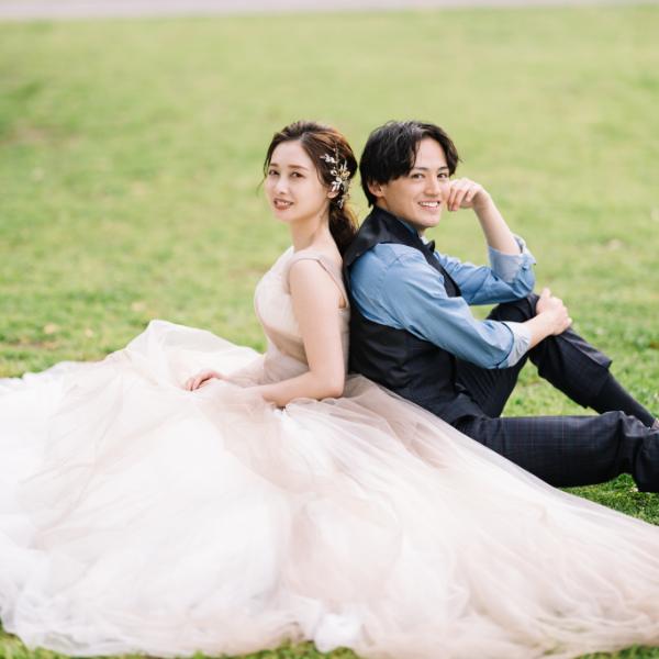 芝生の上に座って微笑む新郎新婦様のウェディングフォト