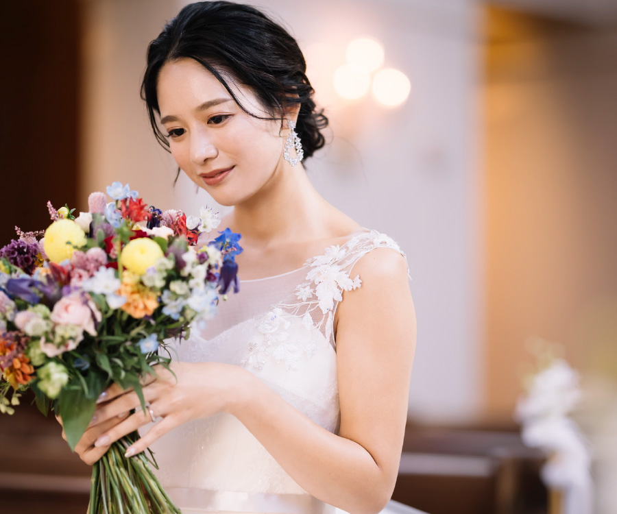 花束を見つめて微笑む新婦様のウェディングフォト