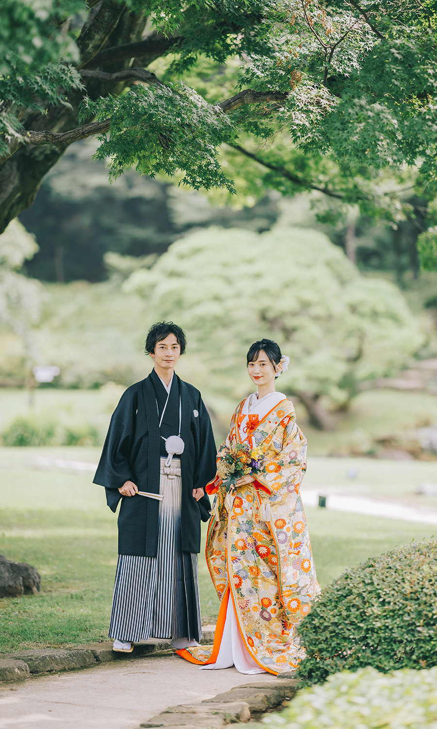 庭園の大きな松の下で微笑む新郎様の結婚写真