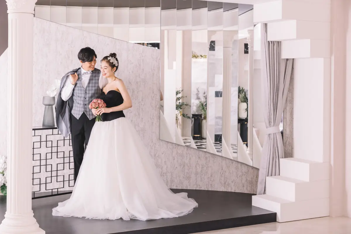 白いスタジオで新婦様に微笑みかける新郎様の結婚写真