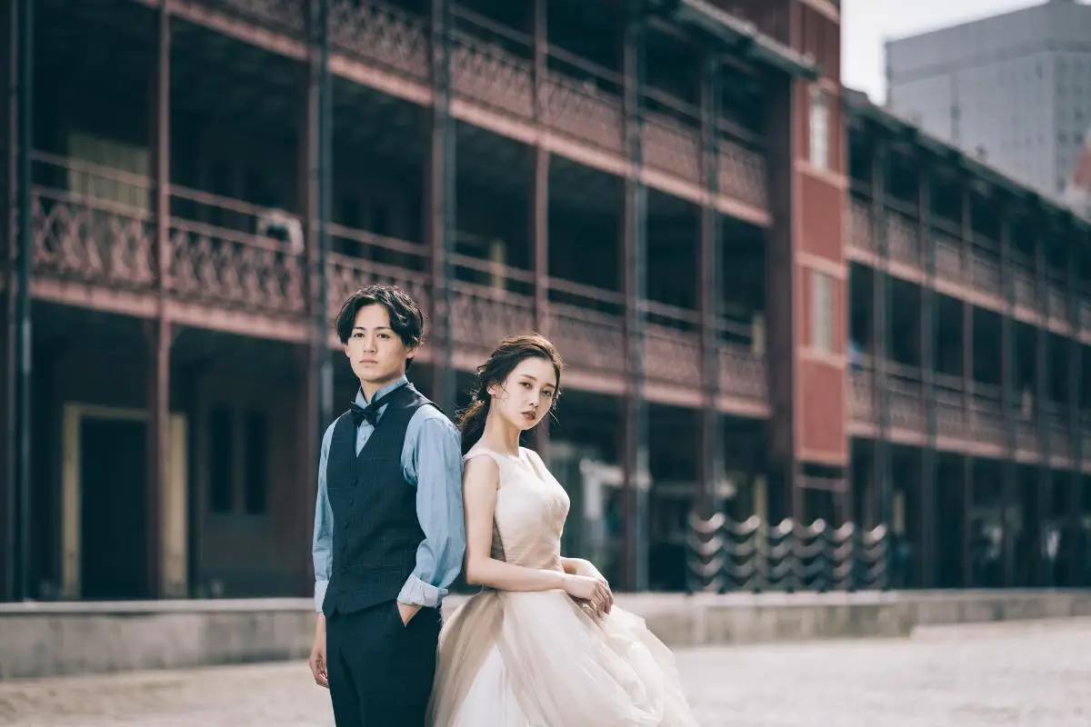 横浜赤レンガ倉庫を背景に背中をあずけあう新郎新婦様のウェディングフォト