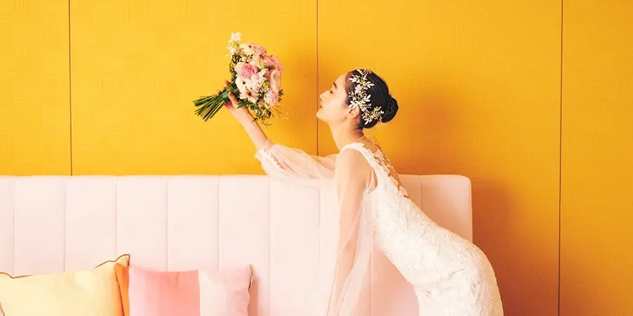 笑顔でブーケを眺める新婦様のウェディングフォト