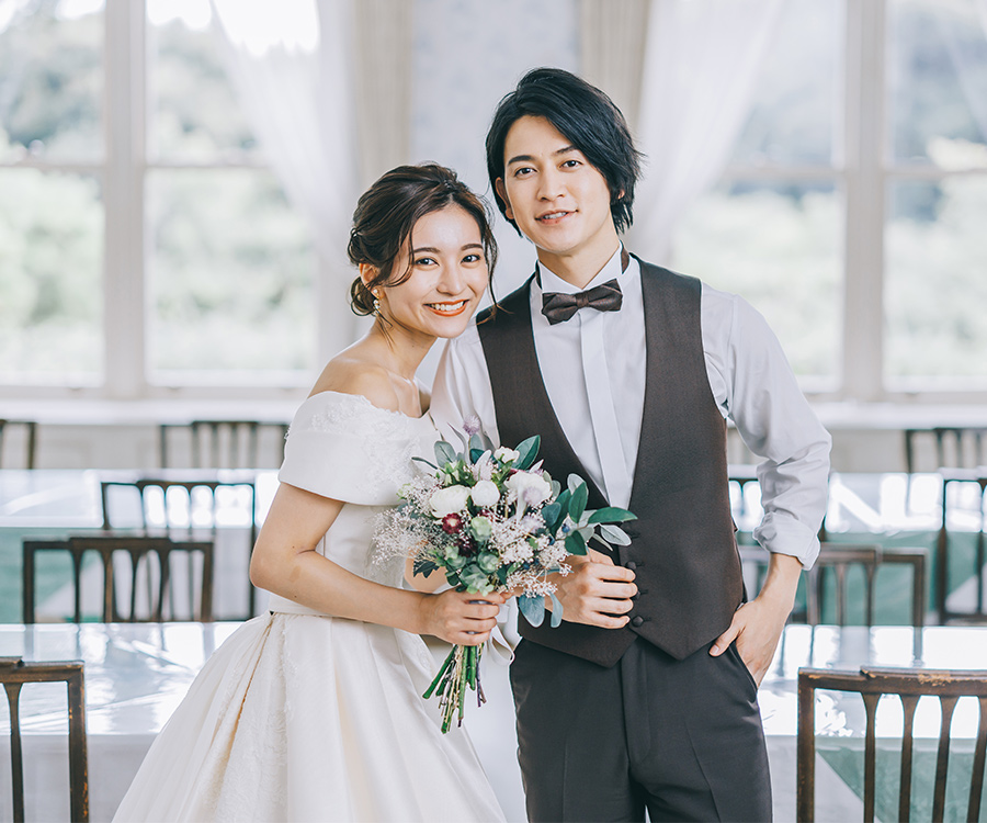 レストランで寄り添う花を持った新婦様と新郎様のウェディングフォト