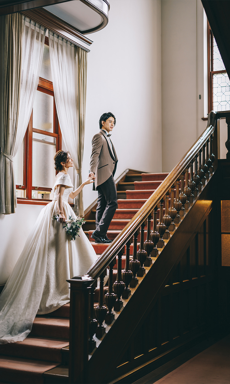 旧古河邸の階段で新婦様の手をとる新郎様のウェディングフォト