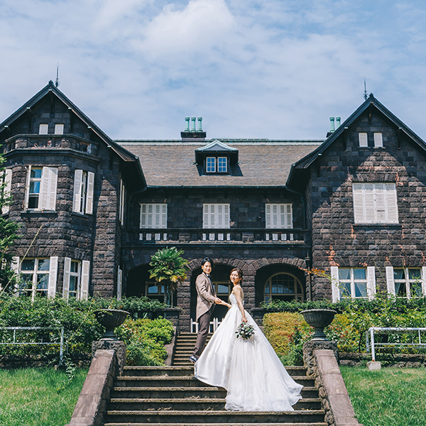 洋館の階段で新婦様の手をとる新郎様の結婚写真