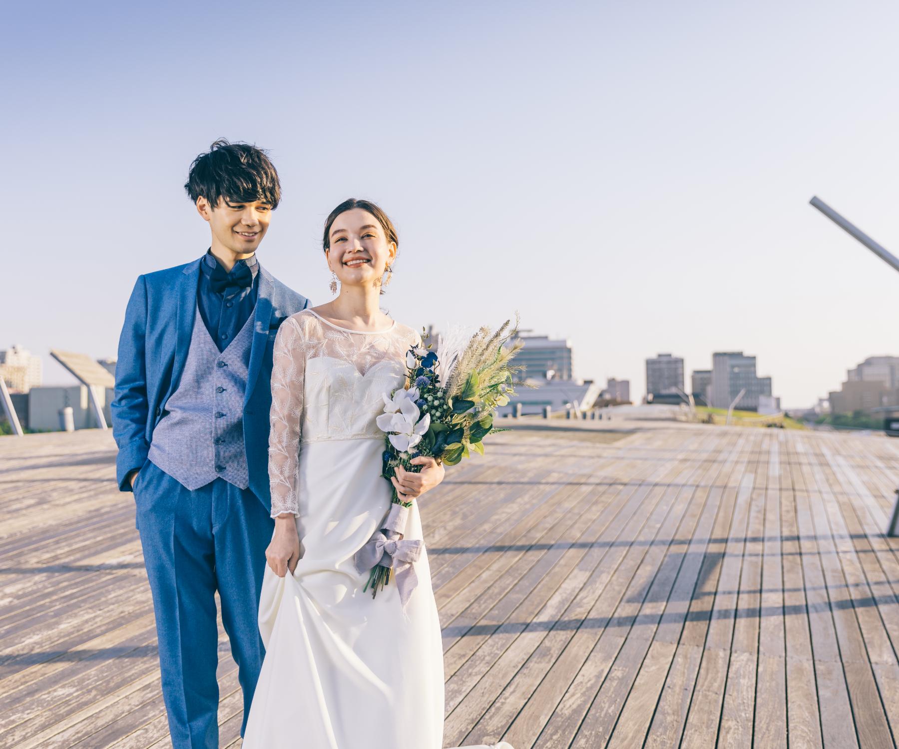 花束をもって微笑む新婦様と新郎様のウェディングフォト