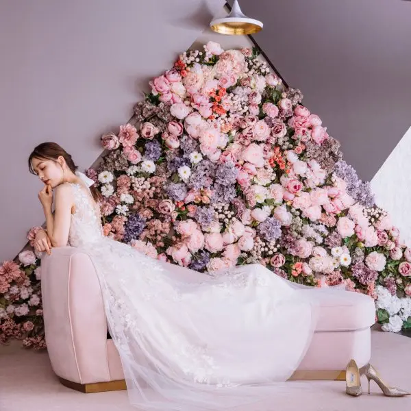 ピンク色のソファに肘を掛ける新婦様のウェディングフォト                    