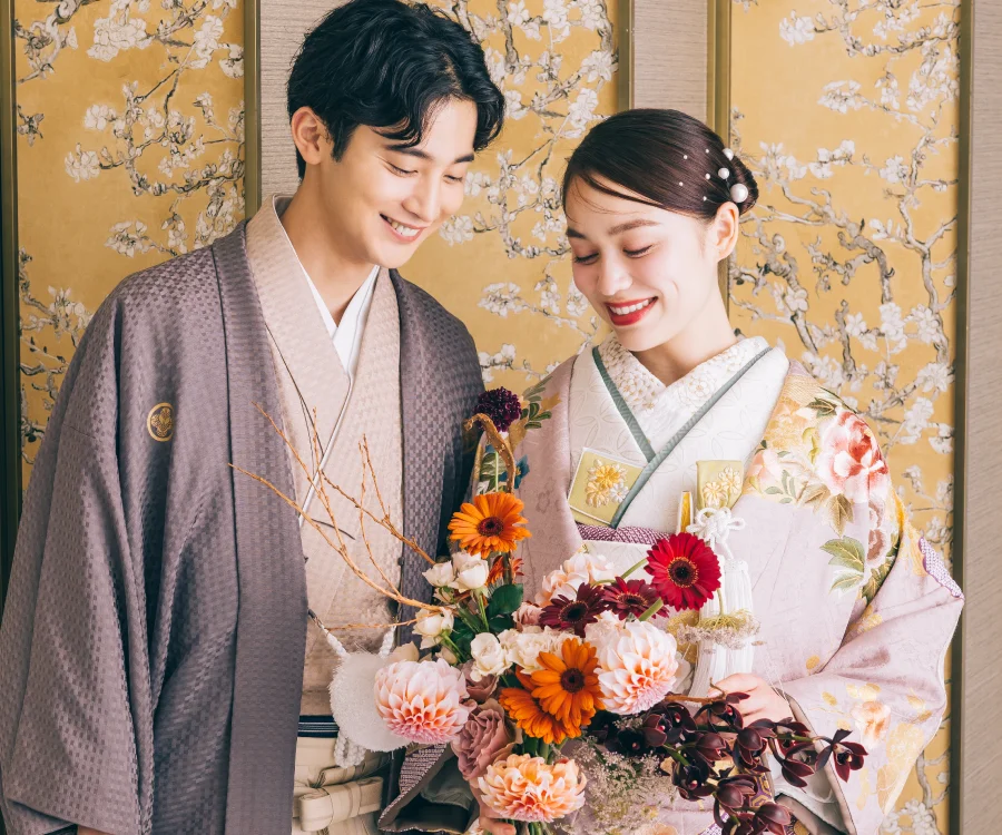 濃淡のあるピンク色のバラをバックにソファに座る新婦様のソロショット                    