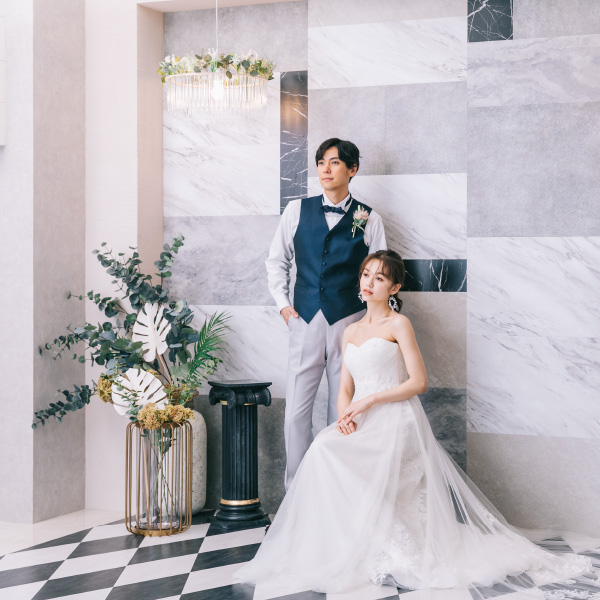大理石の背景セットをバックにポーズをとる新郎新婦様のウェディングフォト